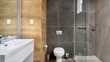 Uma casa de banho moderna com chuveiro, sanita e lavatório.