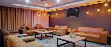 A modern living room with leather sofas, wooden coffee tables, and pendant lighting.