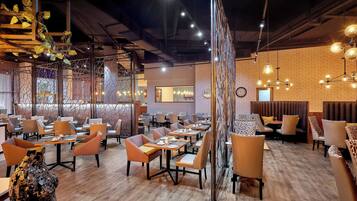 Un restaurante con suelo de madera, sillas naranja y grises, y una pared de ladrillo.