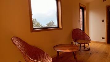 A room with a large window, two wicker chairs, and a small wooden table.
