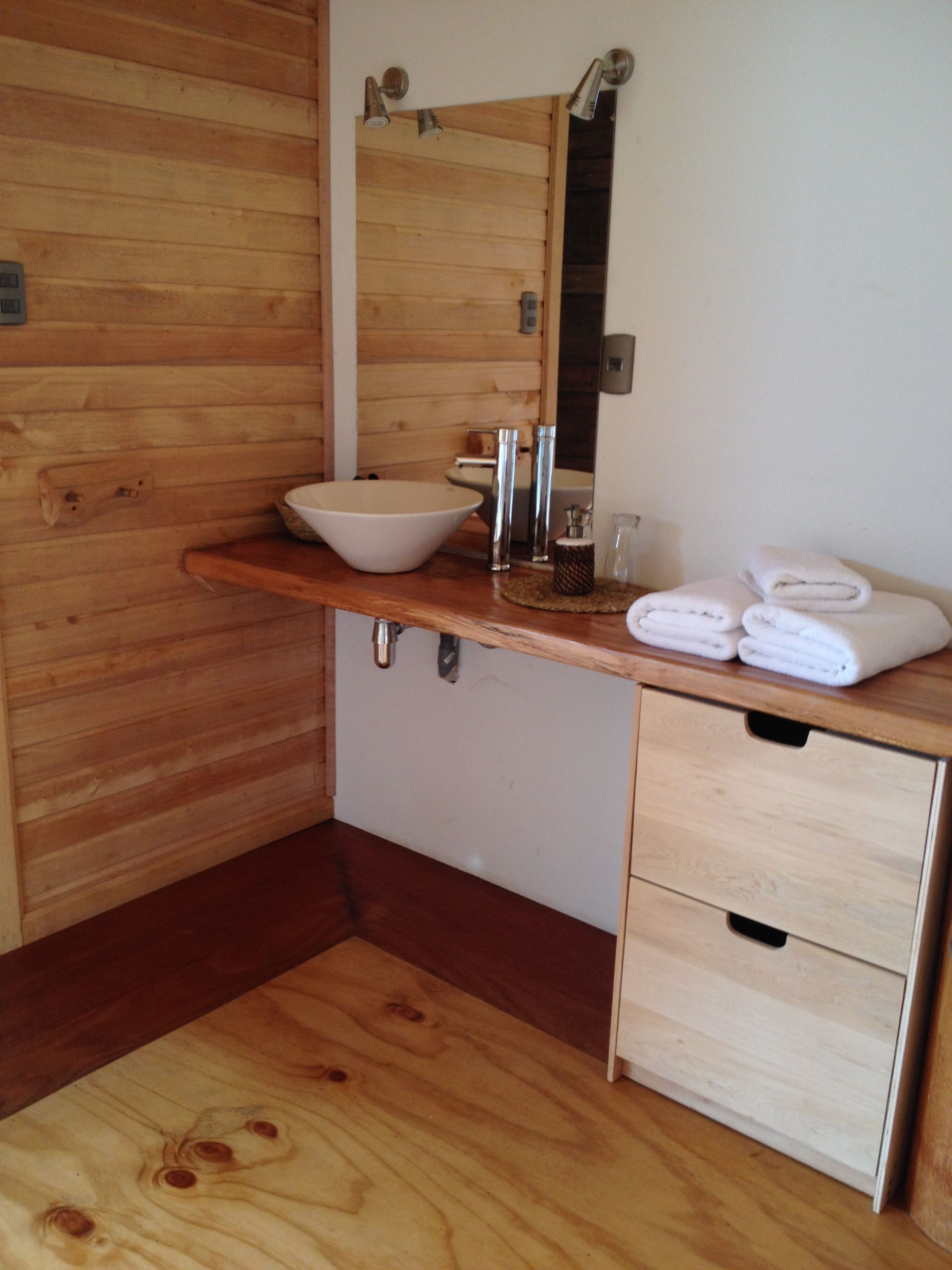 A wooden bathroom with a large sink, mirror, and two drawers.