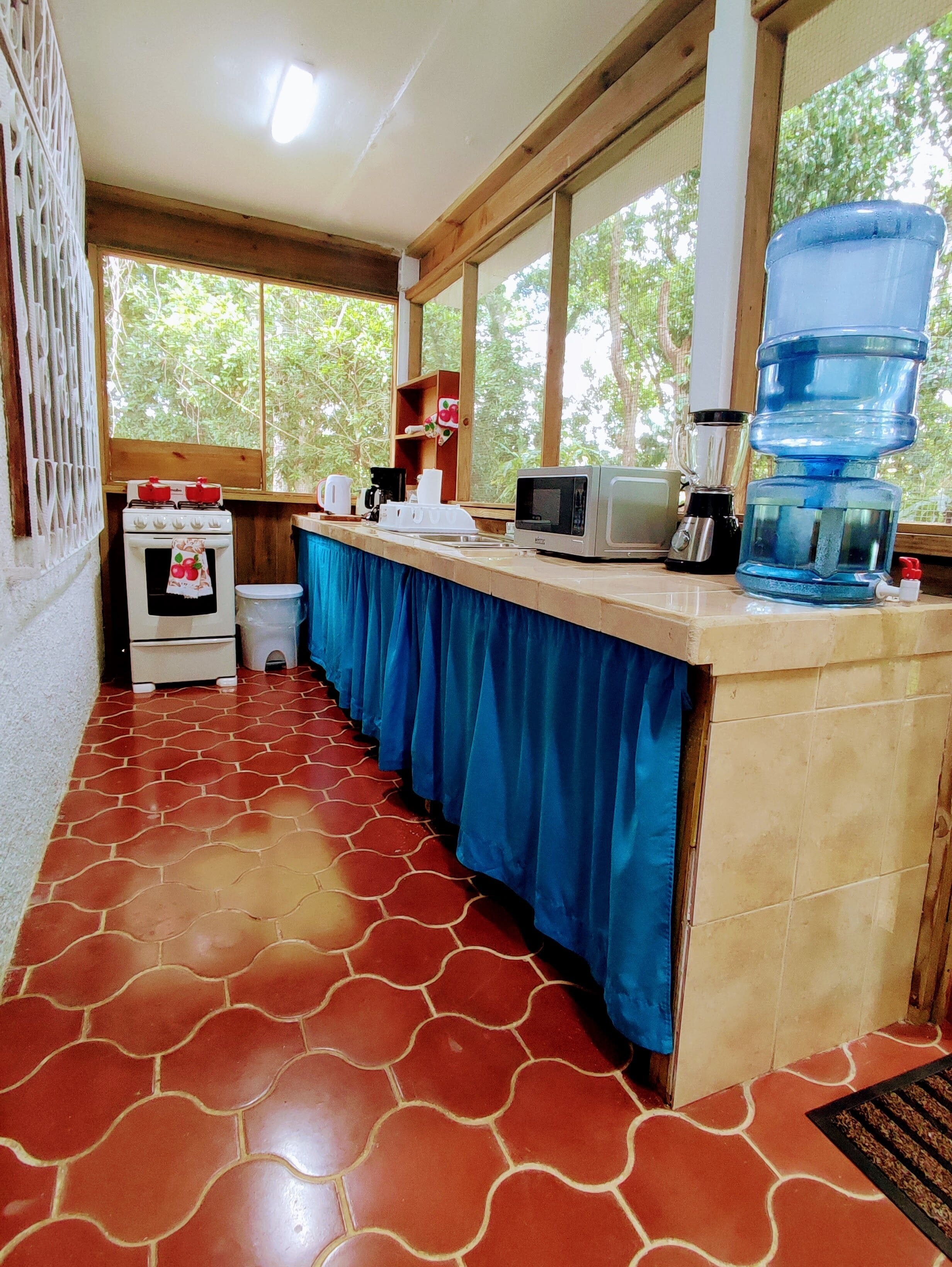 A kitchen with a stove, microwave, coffee maker, and water dispenser.