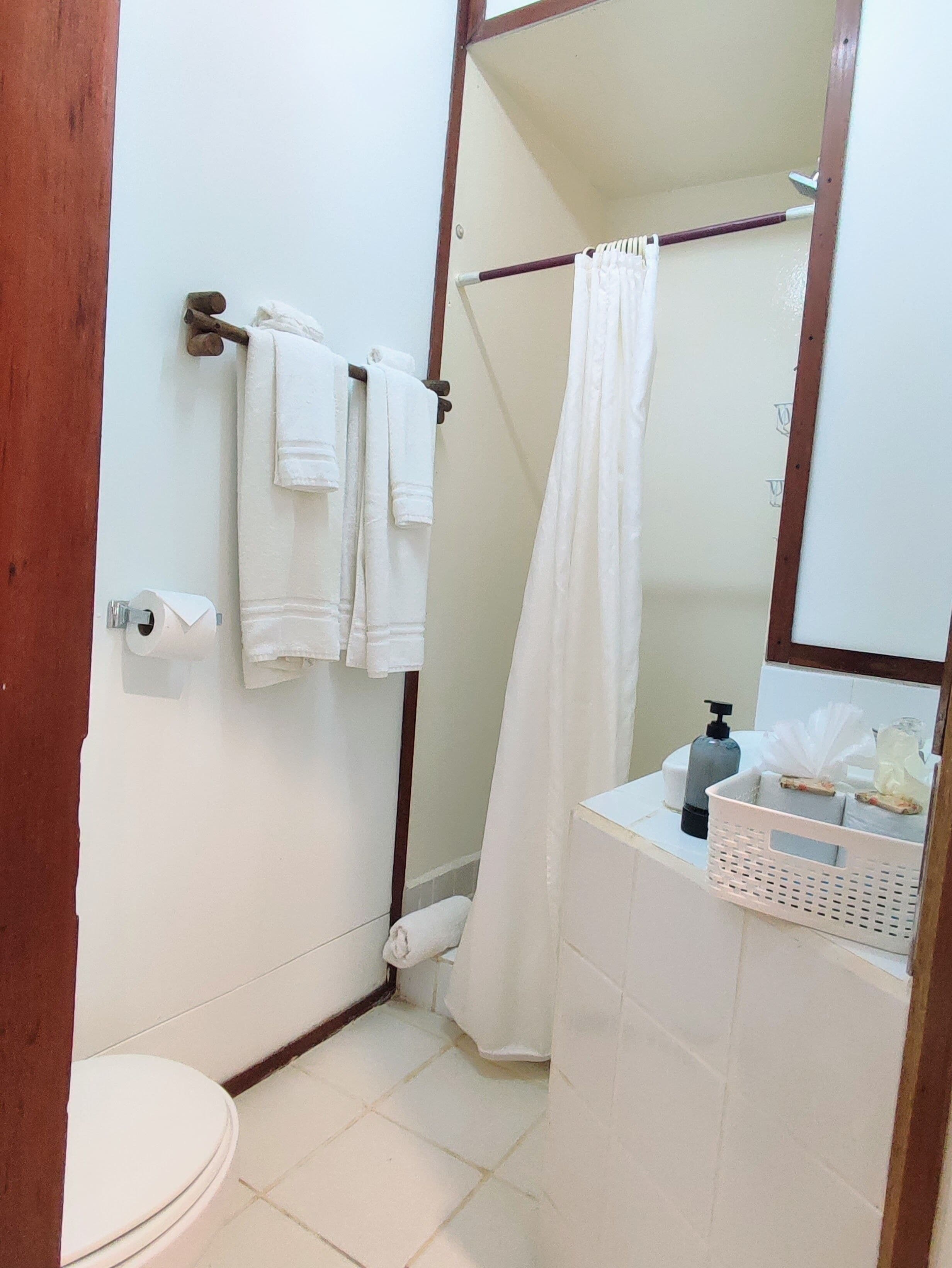 A small bathroom with a toilet, a shower curtain, a towel rack, and a mirror.