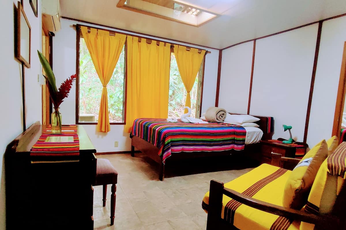 A room with a bed, a desk, and a chair. There is a window with yellow curtains.