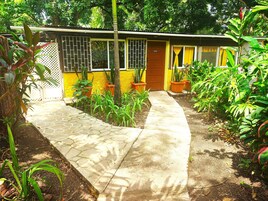 Un pequeño edificio de una sola planta con fachada amarilla y una puerta marrón que dice “OFFICE”.