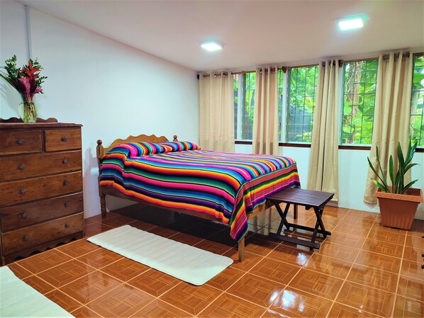 A bedroom with a wooden bed, a dresser, a bench, and a potted plant. - The Maya Mountain Lodge (San Ignacio)