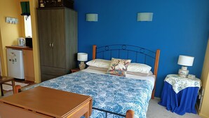 Un dormitorio con cama, una mesa de madera, un armario y un pequeño escritorio.
