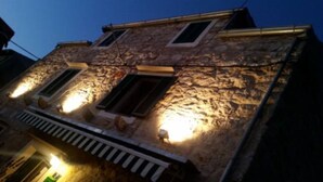 Un edificio de piedra con dos ventanas iluminadas y un pequeño balcón.