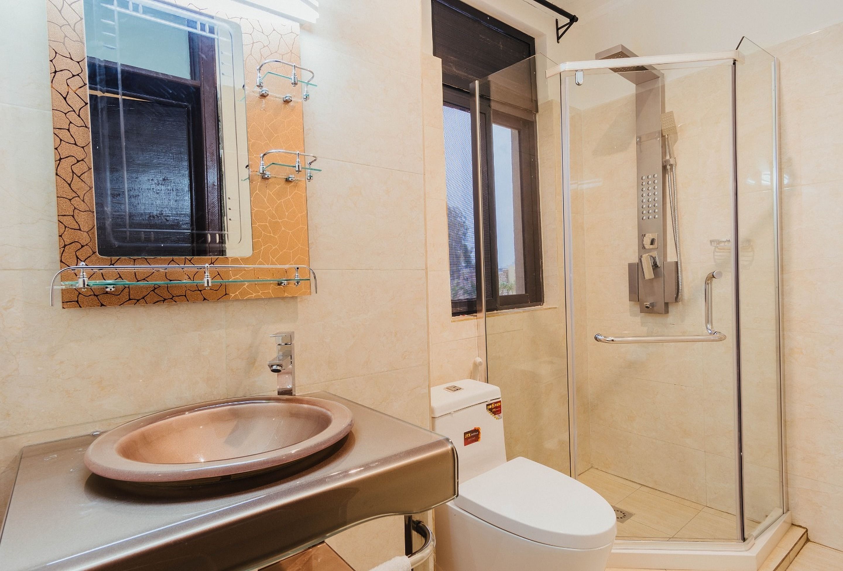 Ein Badezimmer mit einer Duschkabine, einem Waschbecken mit beiger Schüssel und einer Toilette.