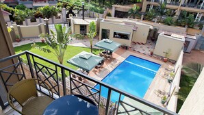 A rooftop pool area with a clear view of the pool, lounge chairs, and surrounding greenery.