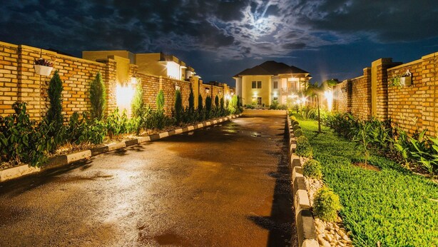 A residential street at night with houses on either side, a well-maintained lawn, and a clear sky.