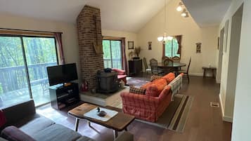 A spacious living room with a fireplace, a television, and a dining area with a chandelier.
