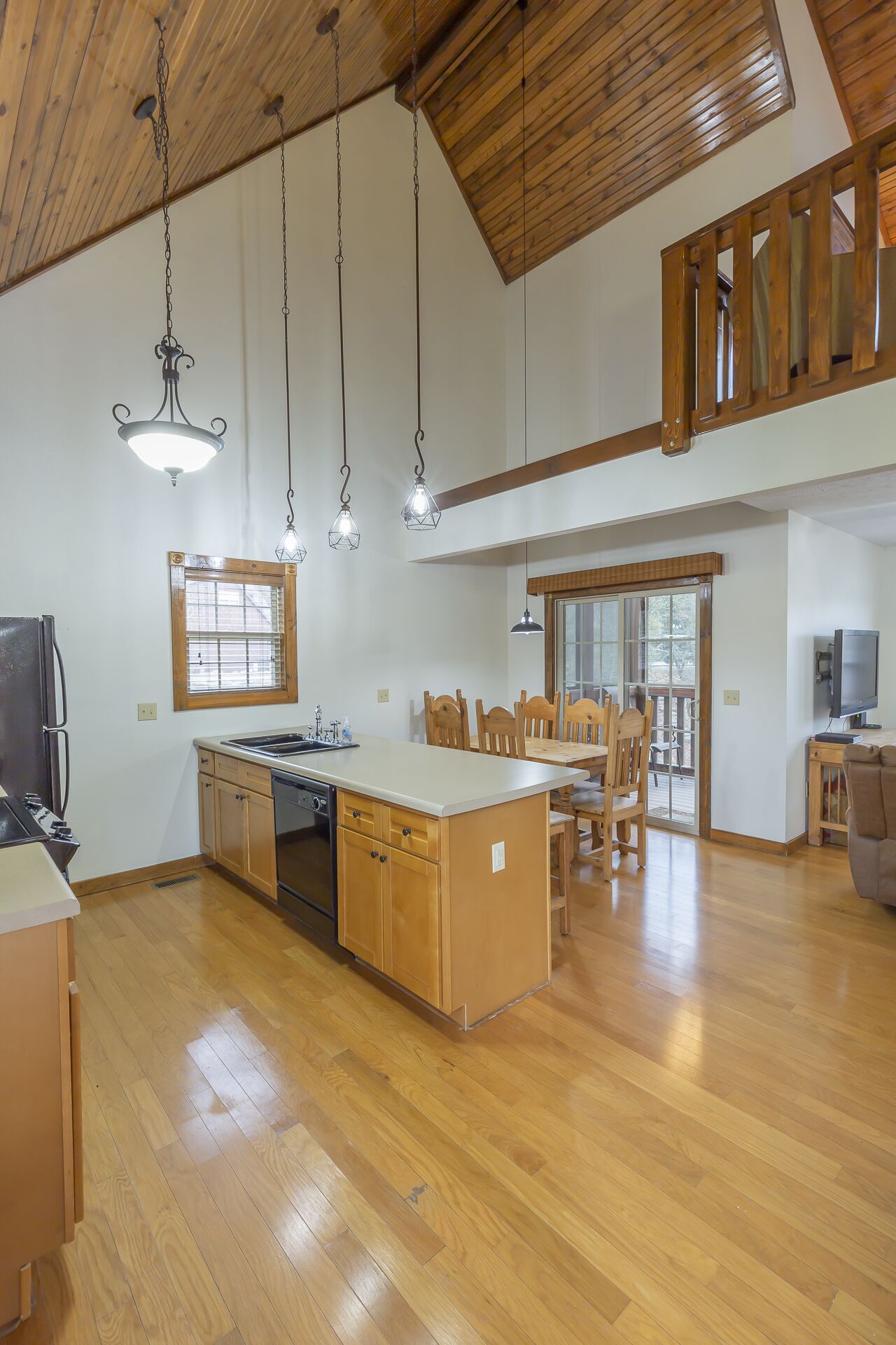 A spacious kitchen with wooden cabinets, a central island, and pendant lighting.