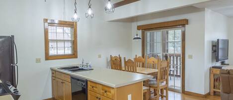 A spacious kitchen with wooden cabinets, a central island, and pendant lighting.