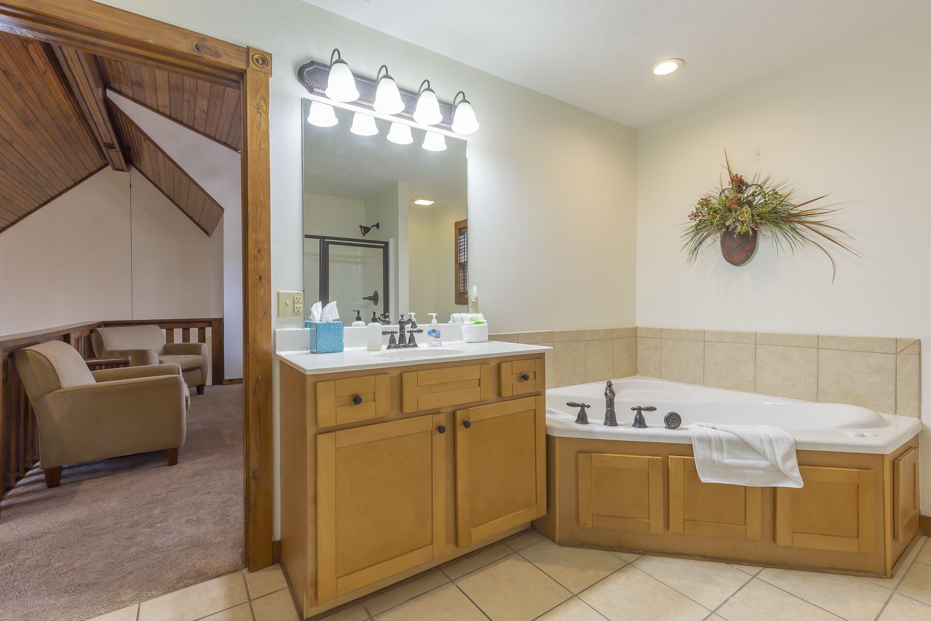 A bathroom with a large mirror, three lights, a sink, and a bathtub.