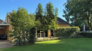 A residential building with a well-maintained lawn, a hedge, and a clear blue sky. - Guesthouse and free wellness in beautiful garden, close to nature and Eindhoven (Leende)