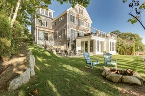 A two-story house with a deck and outdoor seating area. - Waterfront Lake Winnipesaukee Luxury Family House with Private Water-Dock+ more (Meredith)
