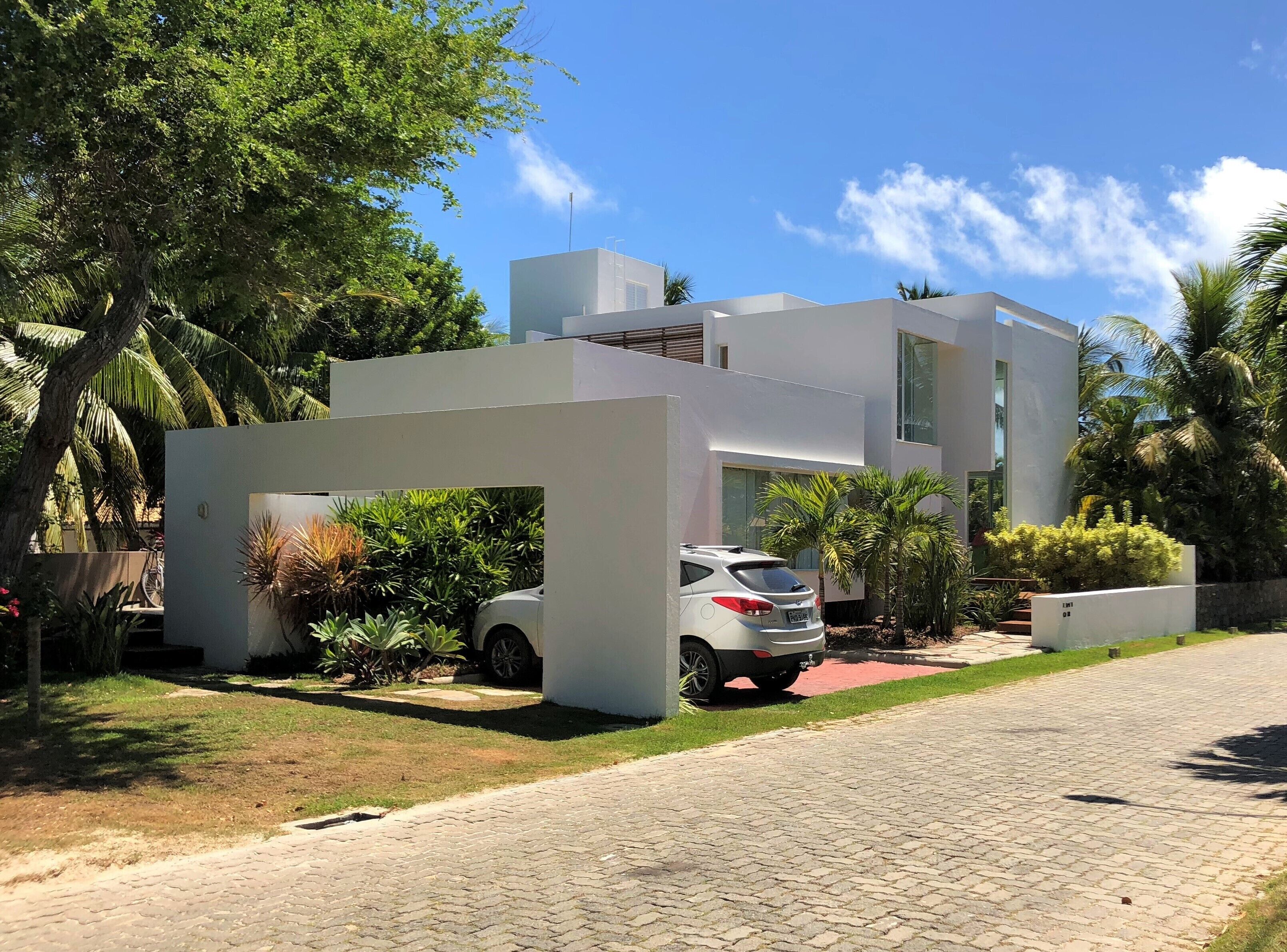 Une maison moderne à deux étages avec une voiture garée dans l’allée.