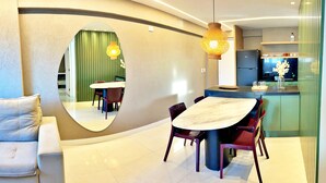 A modern kitchen with a dining area, including a marble table, chairs, and a large mirror. - Vacation - edf. Port Ville III apt 1007 on the top floor with pool panoramic view (Jatiúca)