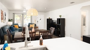 Un salon moderne avec un coin repas, des murs blancs et une grande fenêtre.