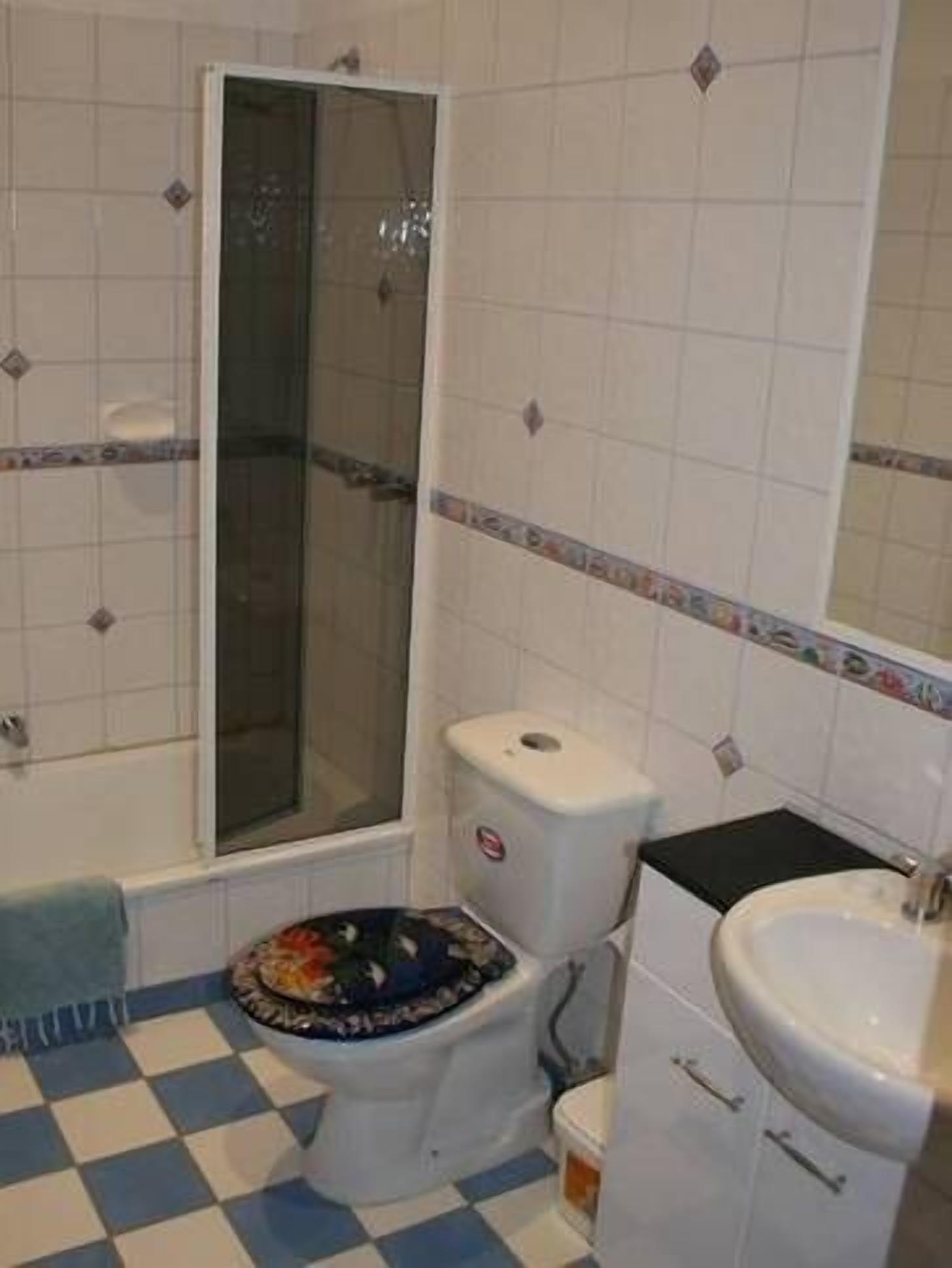 Een badkamer met toilet, wastafel en douche.