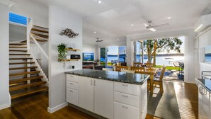 Una cocina moderna con una isla central, suelo de madera y vistas a un lago a través de amplios ventanales.