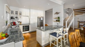 Una cocina moderna con armarios blancos, encimera de granito y refrigerador de acero inoxidable.