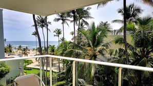 A balcony with a view of a beach and palm trees. - Beautiful Beach Front Condo, Club Hemingway, Juan Dolio, D.R (Juan Dolio)