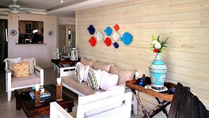 A living room with a white sofa, a wooden coffee table, and a ceiling fan. - Beautiful Beach Front Condo, Club Hemingway, Juan Dolio, D.R (Juan Dolio)