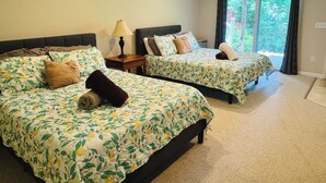 A hotel room with two beds, each with floral bedding, a nightstand with a lamp, and a view of greenery through a large window. - Family Getaway in N. Conway, Sleeps 16, AC, Hot Tub, Game Room, Pets Welcome (Conway)