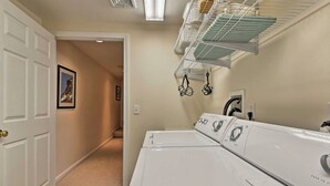 A laundry room with a white door, a hallway, and a wall-mounted drying rack. - Family Getaway in N. Conway, Sleeps 16, AC, Hot Tub, Game Room, Pets Welcome (Conway)