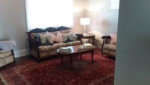 A living room with a sofa, two armchairs, a coffee table, and a lamp. - Cosy cottage on mair (Ballarat)