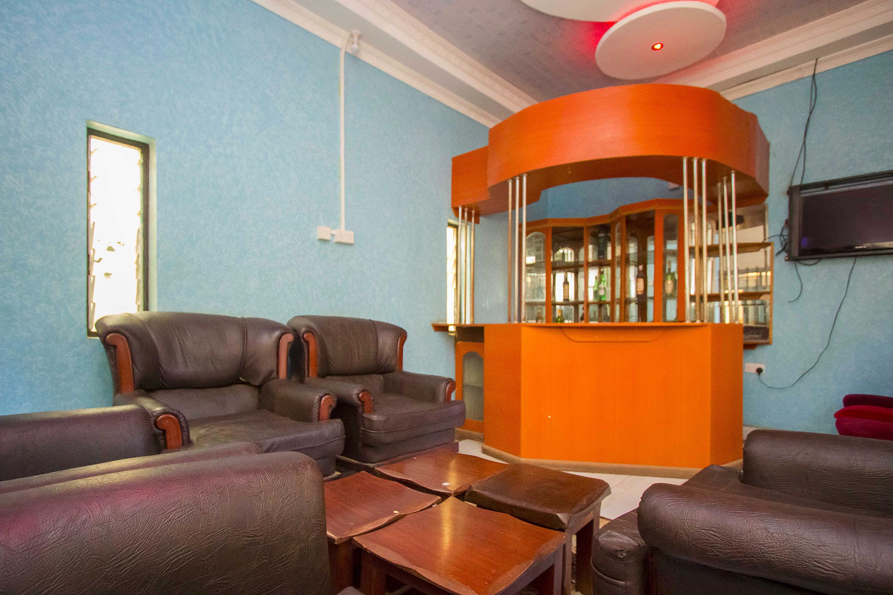 A room with two leather sofas, a wooden coffee table, and a curved orange counter with a glass enclosure.