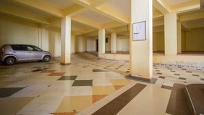 Un estacionamiento interior con un coche, pisos de baldosas y columnas.