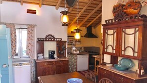 Een kleine keuken met houten kastjes, een eettafel en een hanglamp.