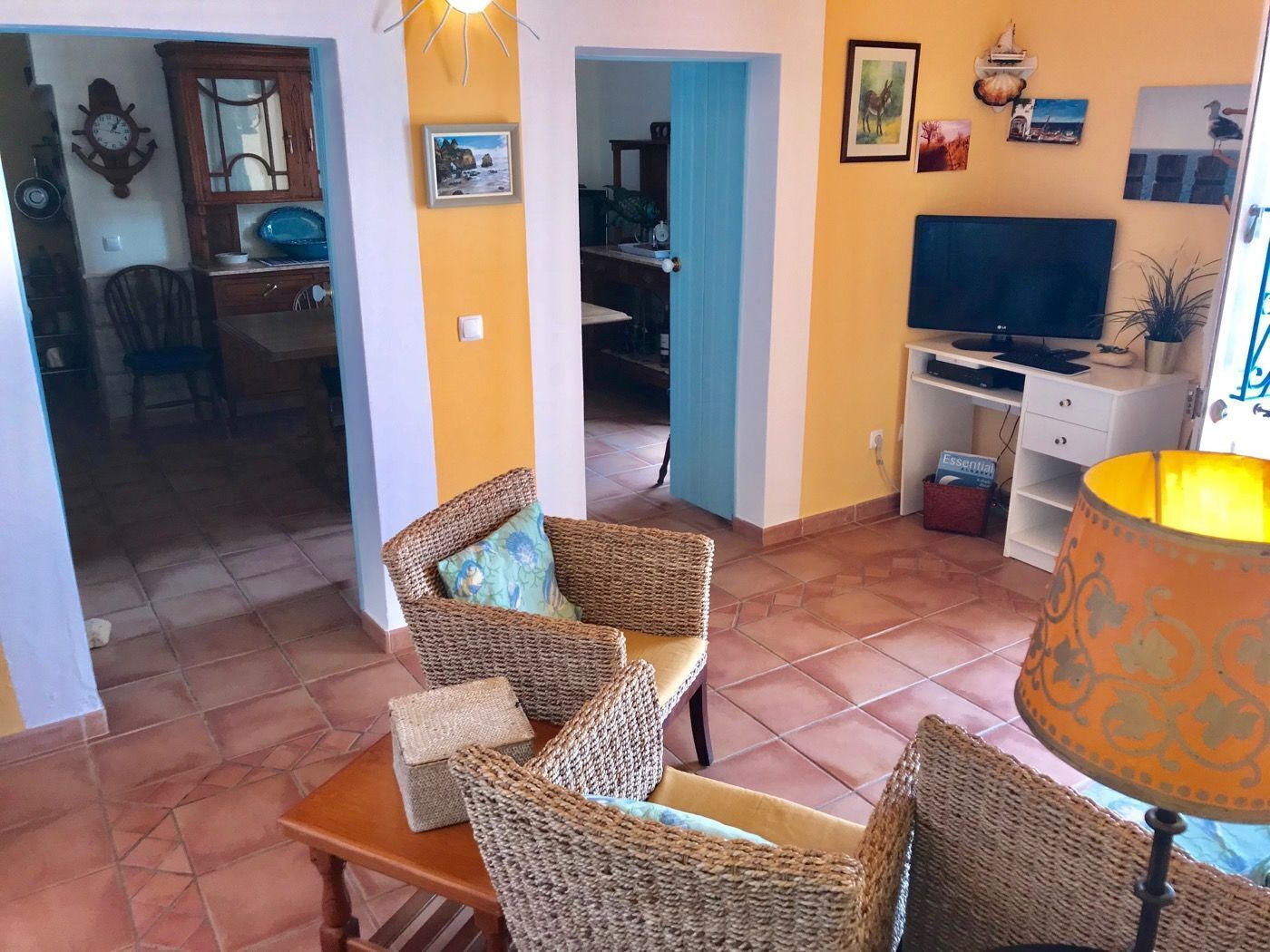 Un salon avec des meubles en osier, un téléviseur et une lampe.
