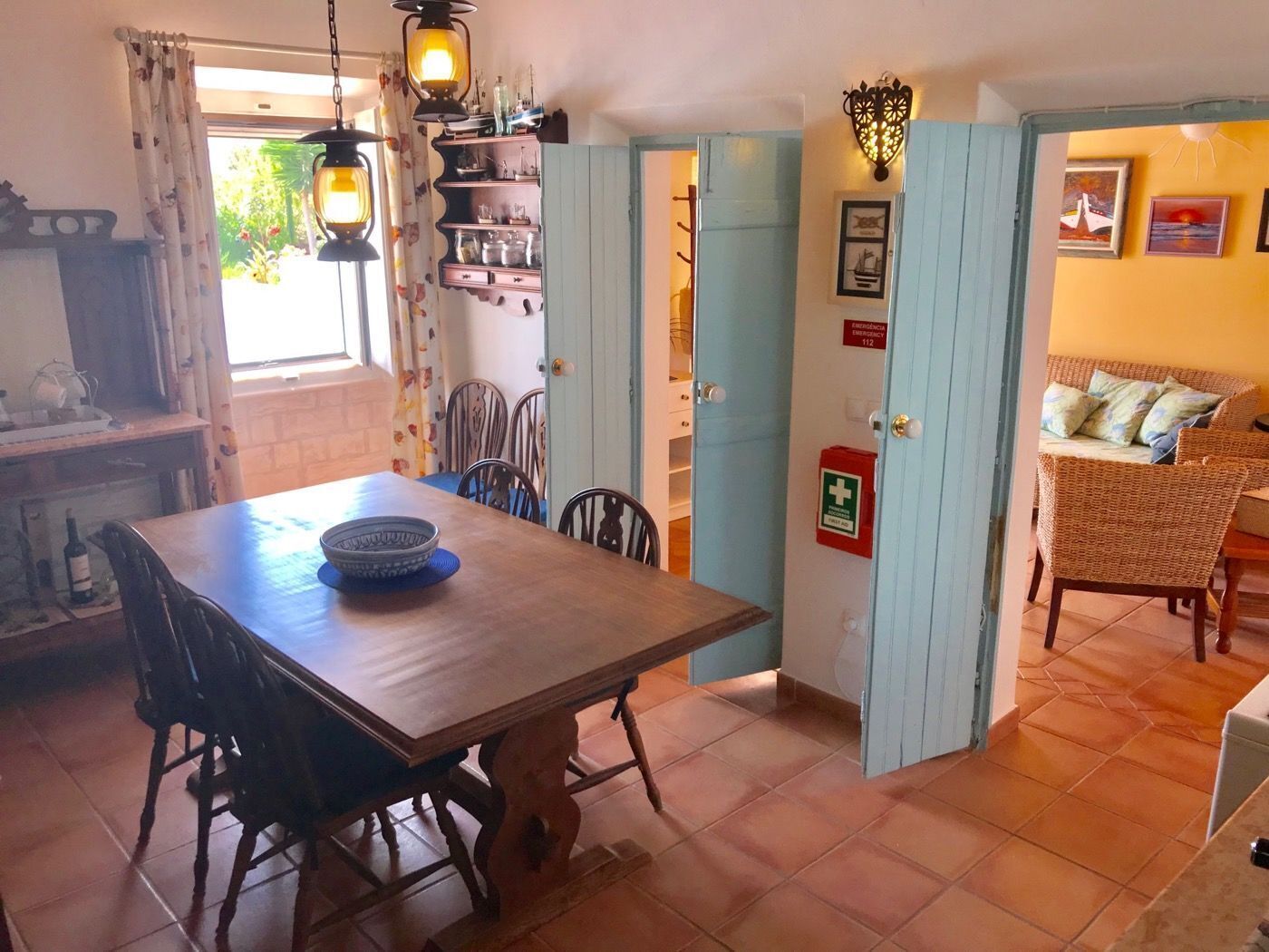Un coin repas avec une table et des chaises en bois, un coin cuisine avec une cuisinière et des placards, et un coin salon avec un canapé et des coussins.