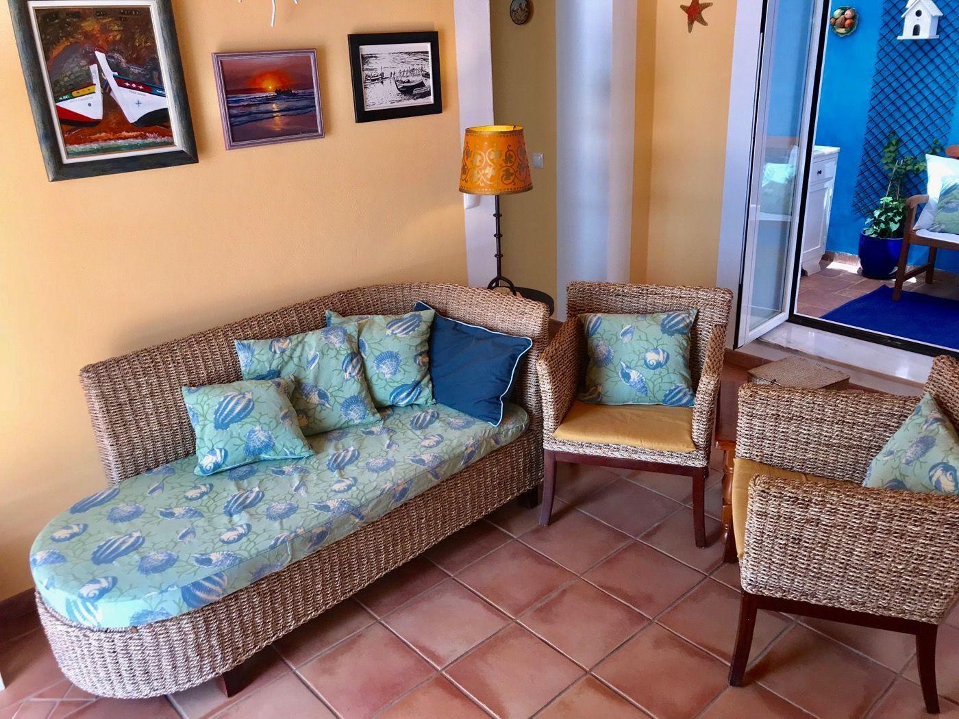 A living room with a wicker sofa, matching armchairs, and a patterned cushion.