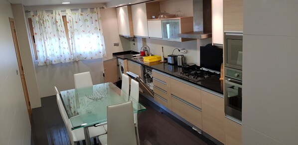 Enjoy meals at the glass-top dining table with stainless steel appliances and ample counter space.