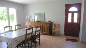 A dining area with a table, chairs, a cabinet, and a door. - Between sea and countryside (Saint-Gatien-Des-Bois)