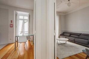 Una sala de estar moderna con una mesa de comedor de cristal, un sofá gris y una mesa de centro blanca.