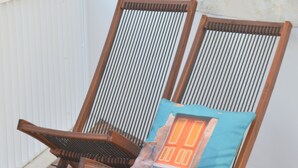 Twee houten loungestoelen met een kussen, geplaatst op een houten terras.