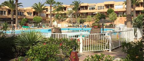 Ein Resort mit Swimmingpool, Palmen und einem Gebäude mit Balkonen.