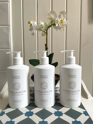 Three bottles of Essence of Harris products on a tiled surface with a white orchid in the background.