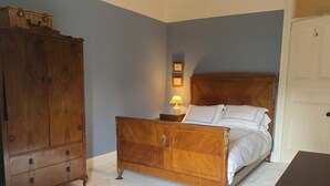Une chambre à coucher avec un lit en bois, une table de chevet avec une lampe, une armoire et une porte.