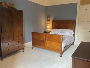 A bedroom with a wooden bed, a nightstand with a lamp, a wardrobe, and a door.