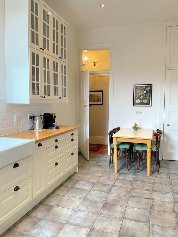 A kitchen with white cabinets, a wooden countertop, and a dining area with a table and chairs.