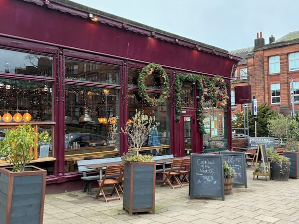 A restaurant with outdoor seating, a chalkboard menu, and festive decorations.