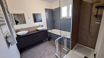 Une salle de bain moderne avec une douche à l’italienne, une baignoire et deux lavabos.