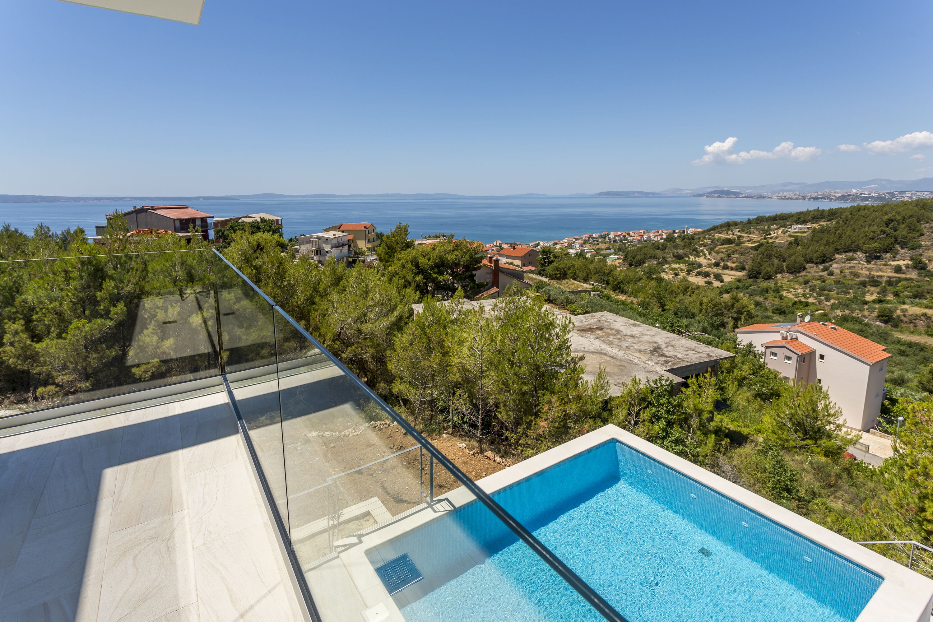 Una piscina en la azotea con vistas despejadas al mar y edificios circundantes.